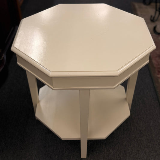 Octagonal side table with a white finish on a dark floor.
