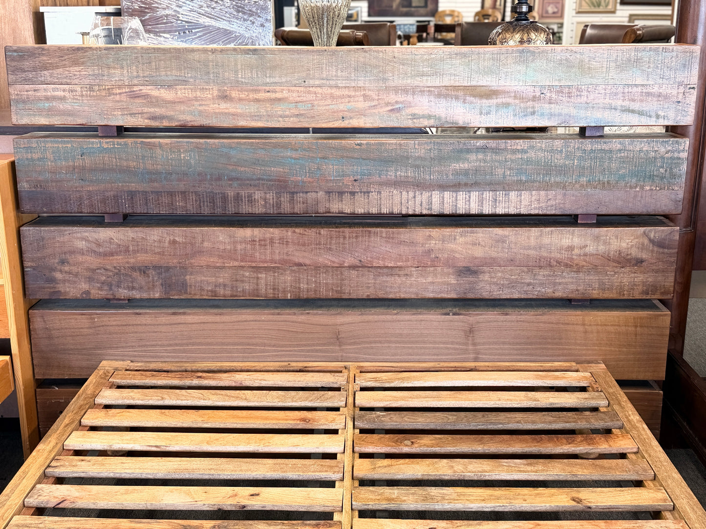 Wooden headboard and footboard with a rustic finish in a room setting.