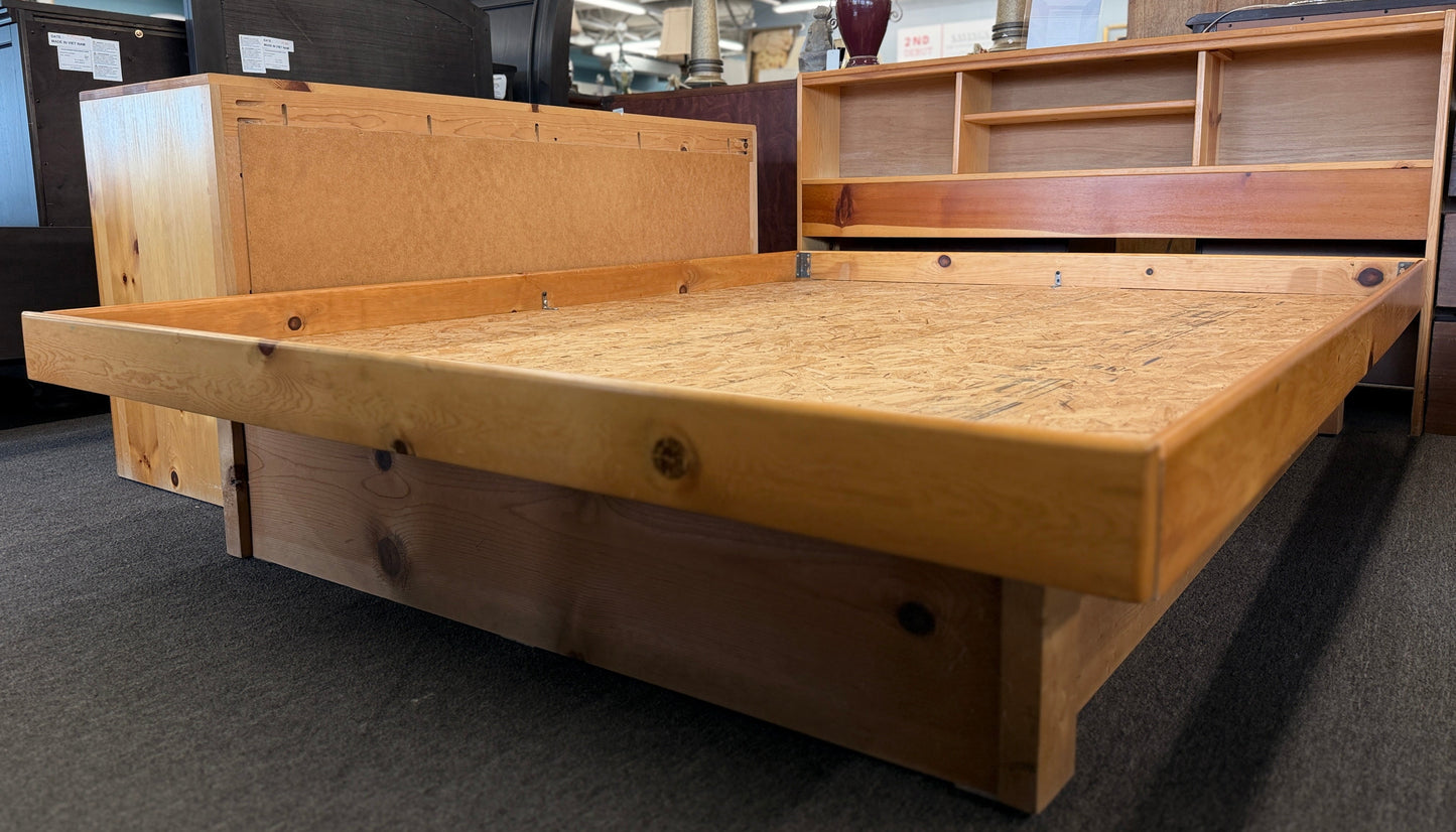 Wooden bed frame in a store setting with other furniture items.