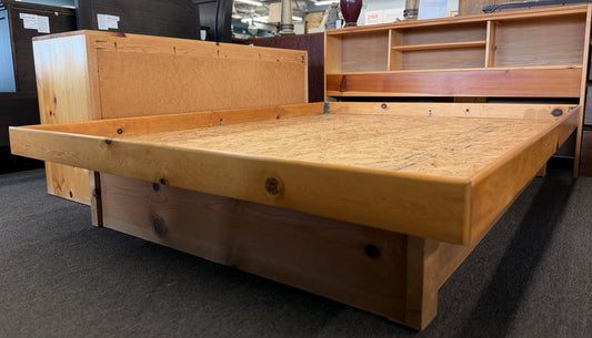 Wooden bed frame in a store setting with other furniture items.