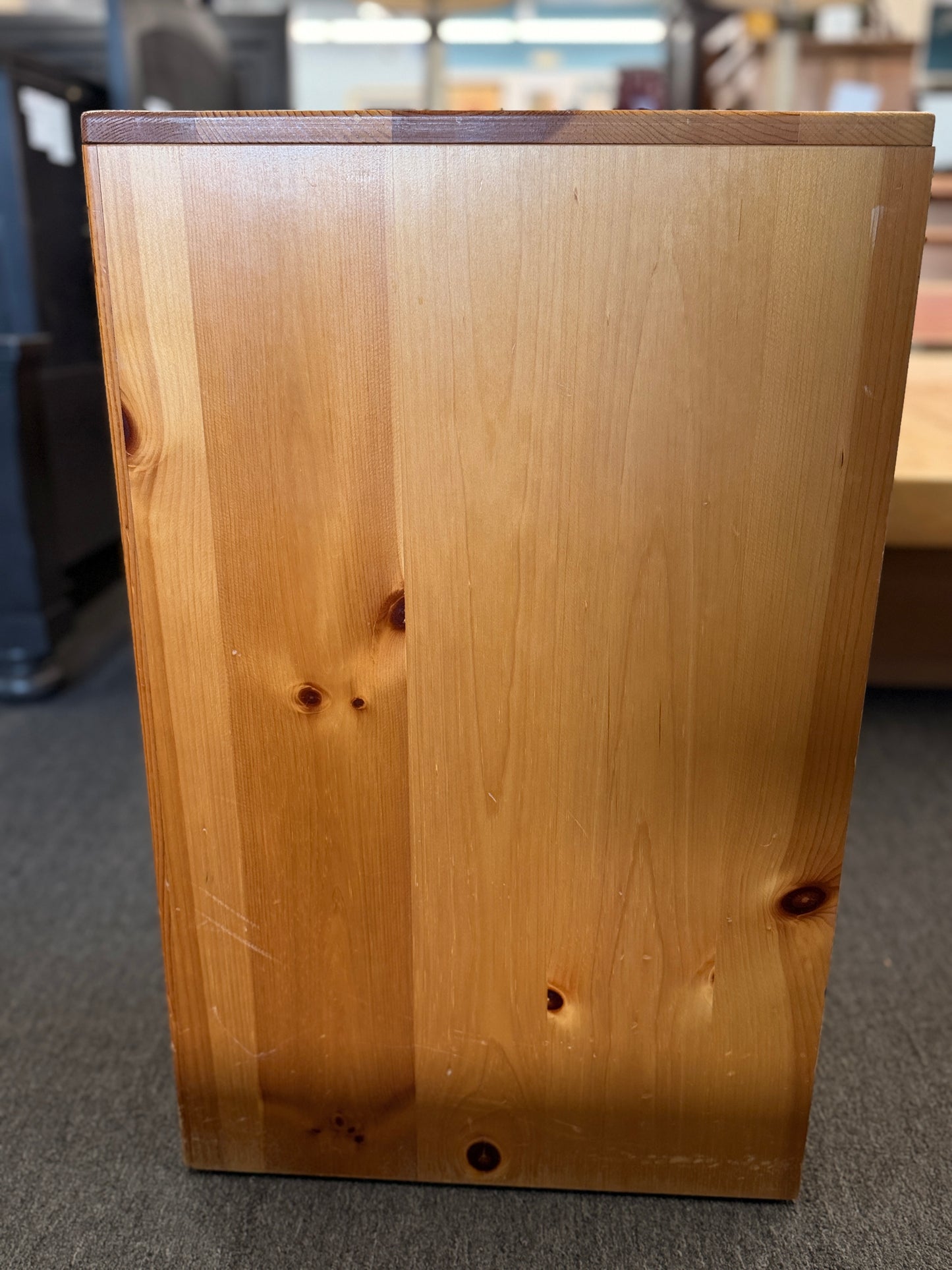 Wooden cabinet with a dark brown top and light brown body on a gray floor.