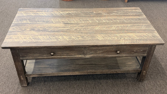 Wooden coffee table with a rustic finish on a carpeted floor