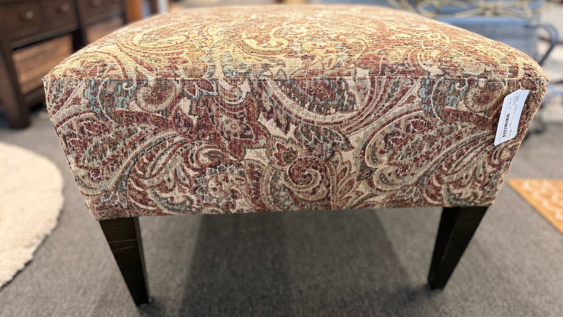Patterned ottoman on a carpeted floor with furniture in the background