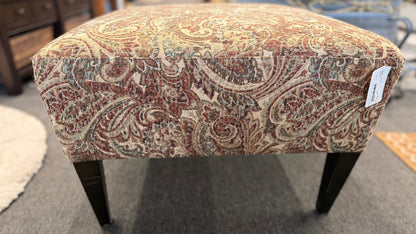 Patterned ottoman on a carpeted floor with furniture in the background