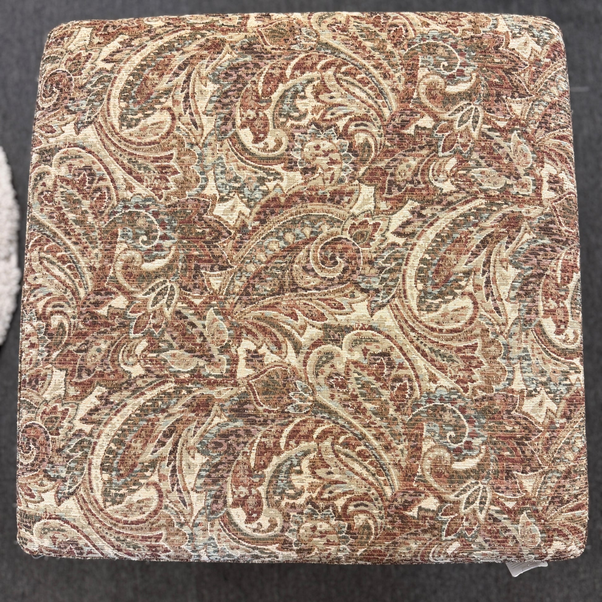 Square fabric swatch with intricate paisley pattern on a dark background