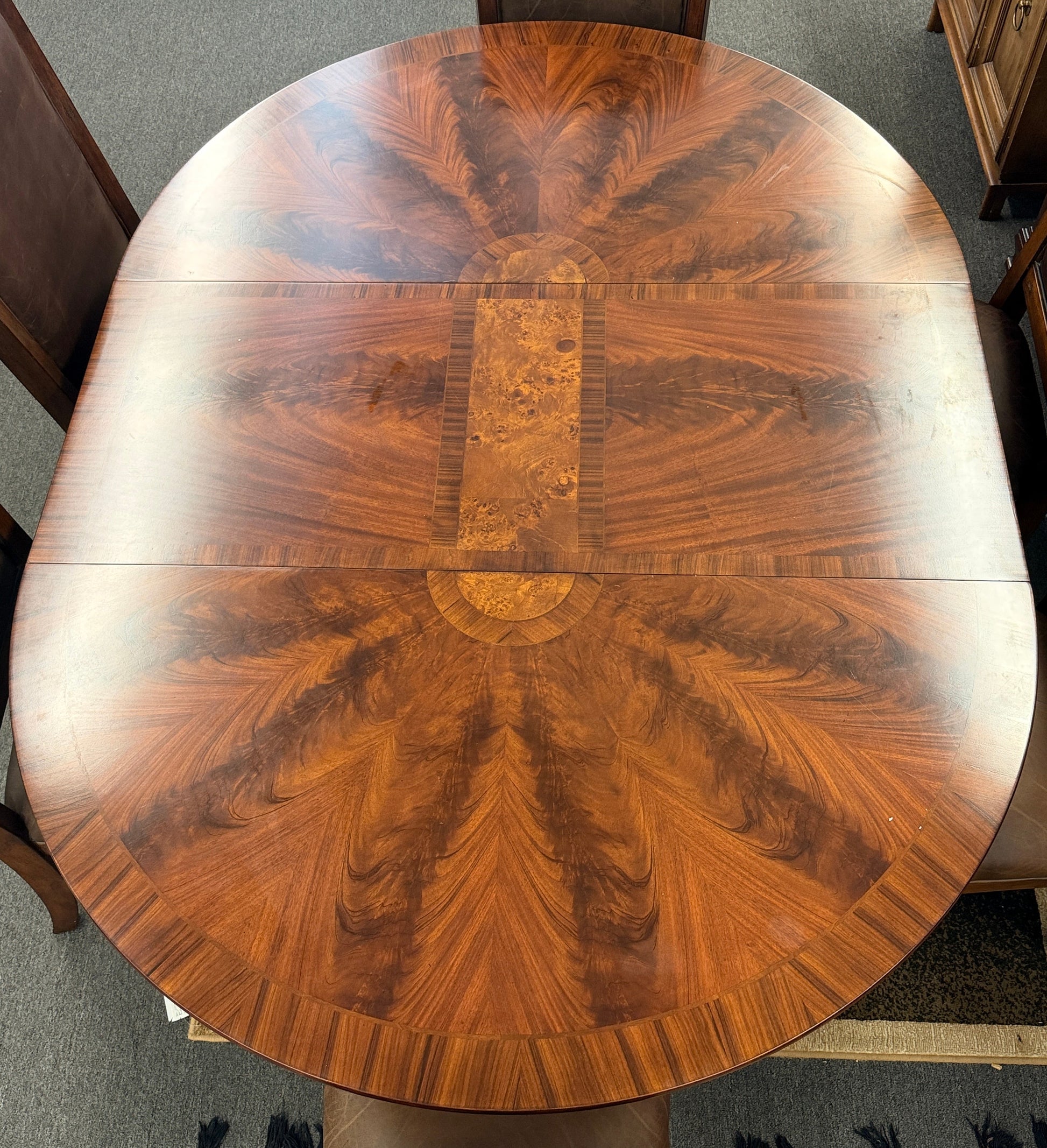 A formal 7-piece dining set featuring an oval dark wood extension table with a carved pedestal base and six upholstered high-back chairs with rolled silhouettes.