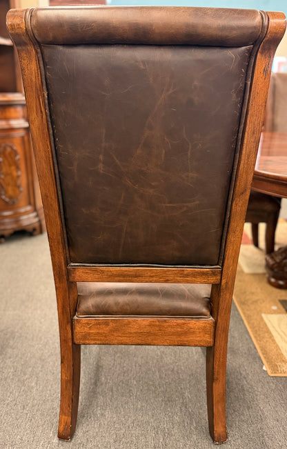 A formal 7-piece dining set featuring an oval dark wood extension table with a carved pedestal base and six upholstered high-back chairs with rolled silhouettes.