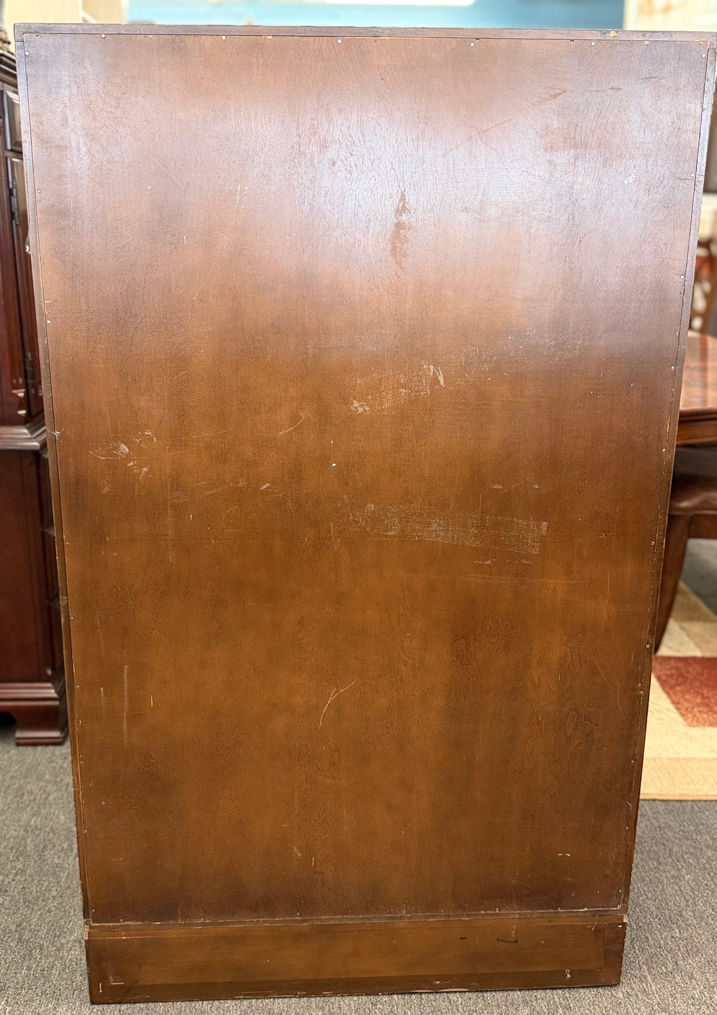 A vintage wooden armoire storage cabinet featuring a symmetric four-panel door facade with recessed molding and antiqued brass ring pull handles.