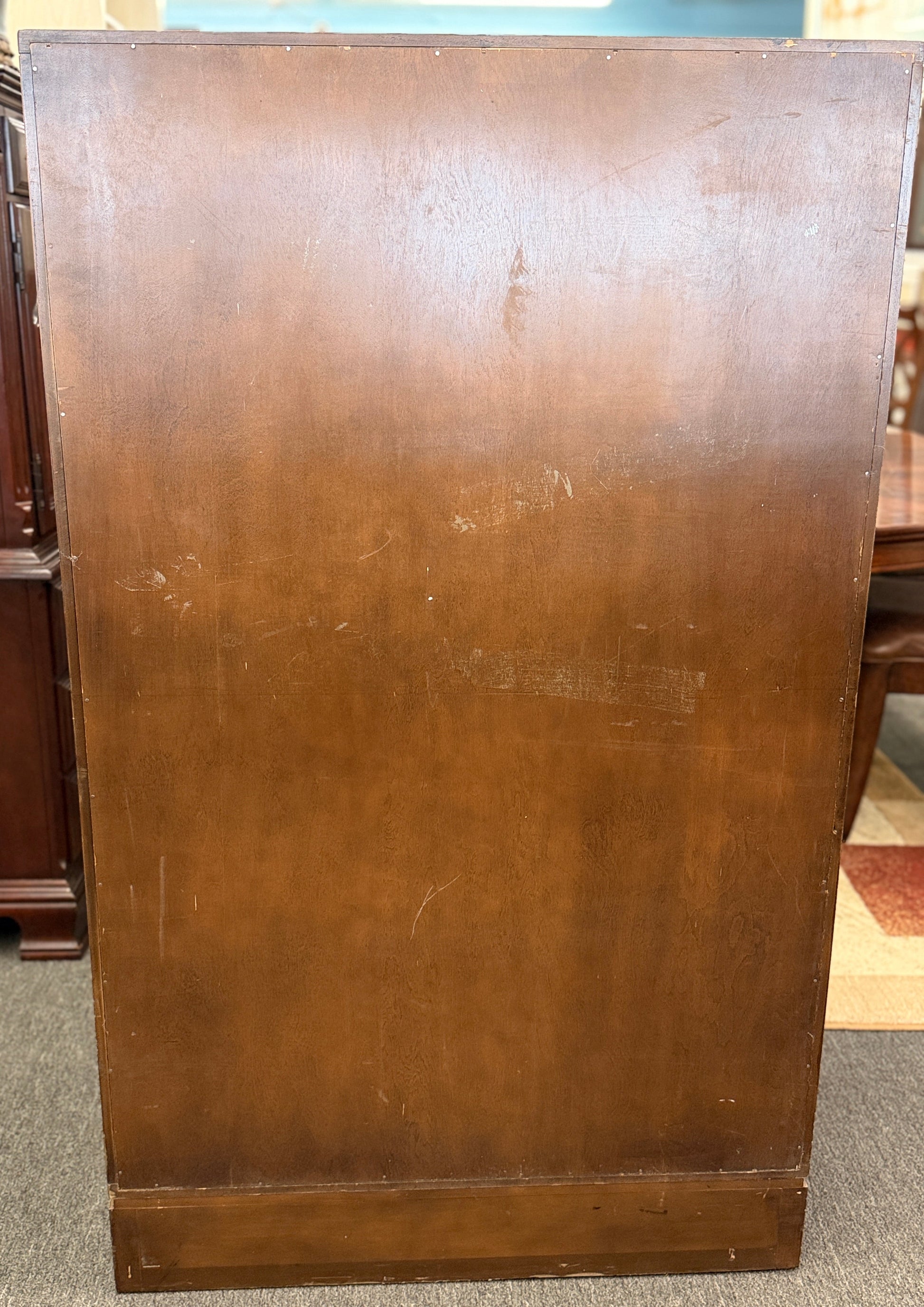 A vintage wooden armoire storage cabinet featuring a symmetric four-panel door facade with recessed molding and antiqued brass ring pull handles.