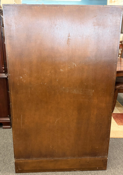 A vintage wooden armoire storage cabinet featuring a symmetric four-panel door facade with recessed molding and antiqued brass ring pull handles.