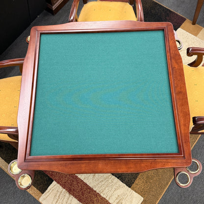 A 5-piece traditional game table set featuring a square wood table with a green felt surface and cup holders, surrounded by four rolling armchairs in yellow patterned upholstery with a Greek key trim.