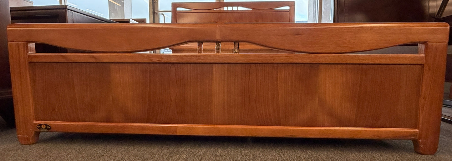 A mid-century modern full bed frame made of wood, featuring a gently curved headboard, footboard, and a sturdy interior slatted support base.