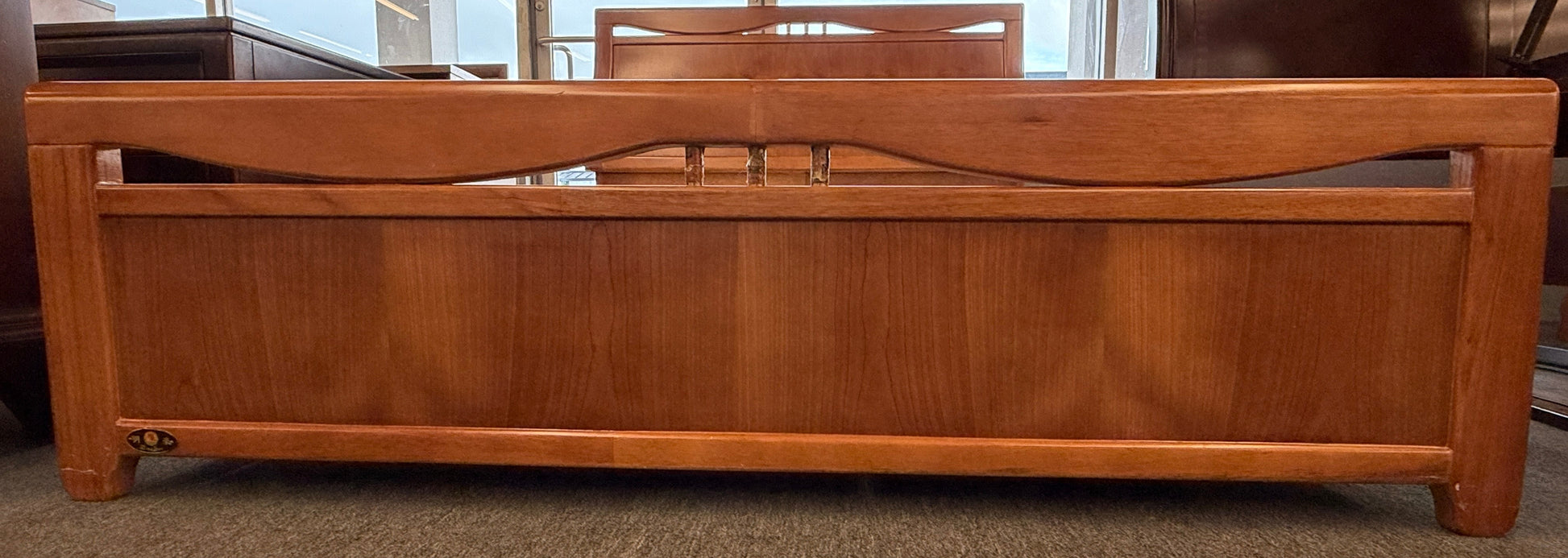 A mid-century modern full bed frame made of wood, featuring a gently curved headboard, footboard, and a sturdy interior slatted support base.