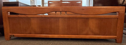A mid-century modern full bed frame made of wood, featuring a gently curved headboard, footboard, and a sturdy interior slatted support base.
