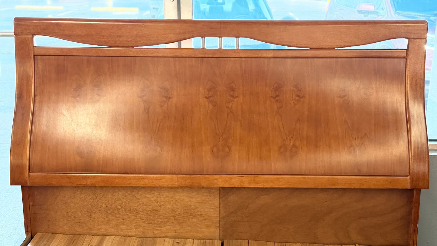 A mid-century modern full bed frame made of wood, featuring a gently curved headboard, footboard, and a sturdy interior slatted support base.