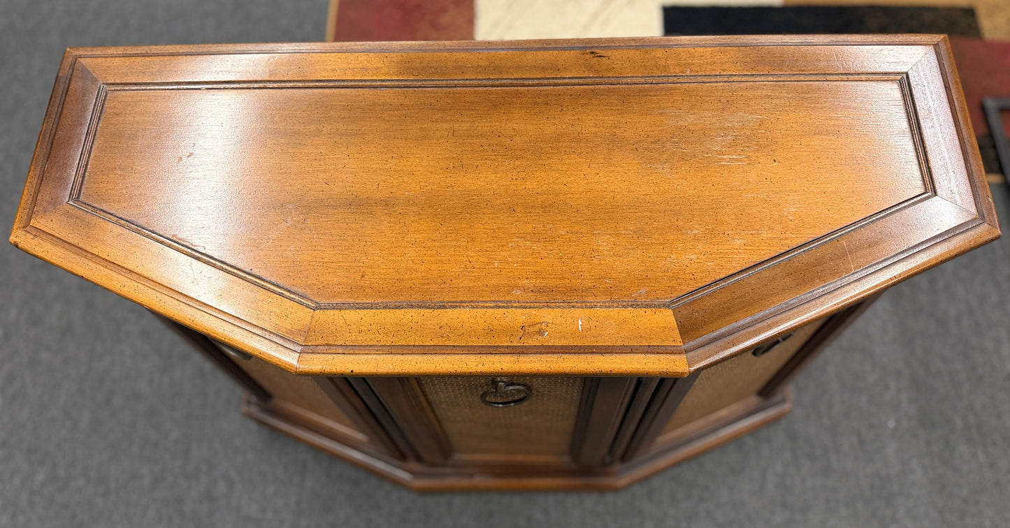 A classic wood accent cabinet featuring three front panels with decorative metal ring-pull hardware and a clean-lined wood frame.