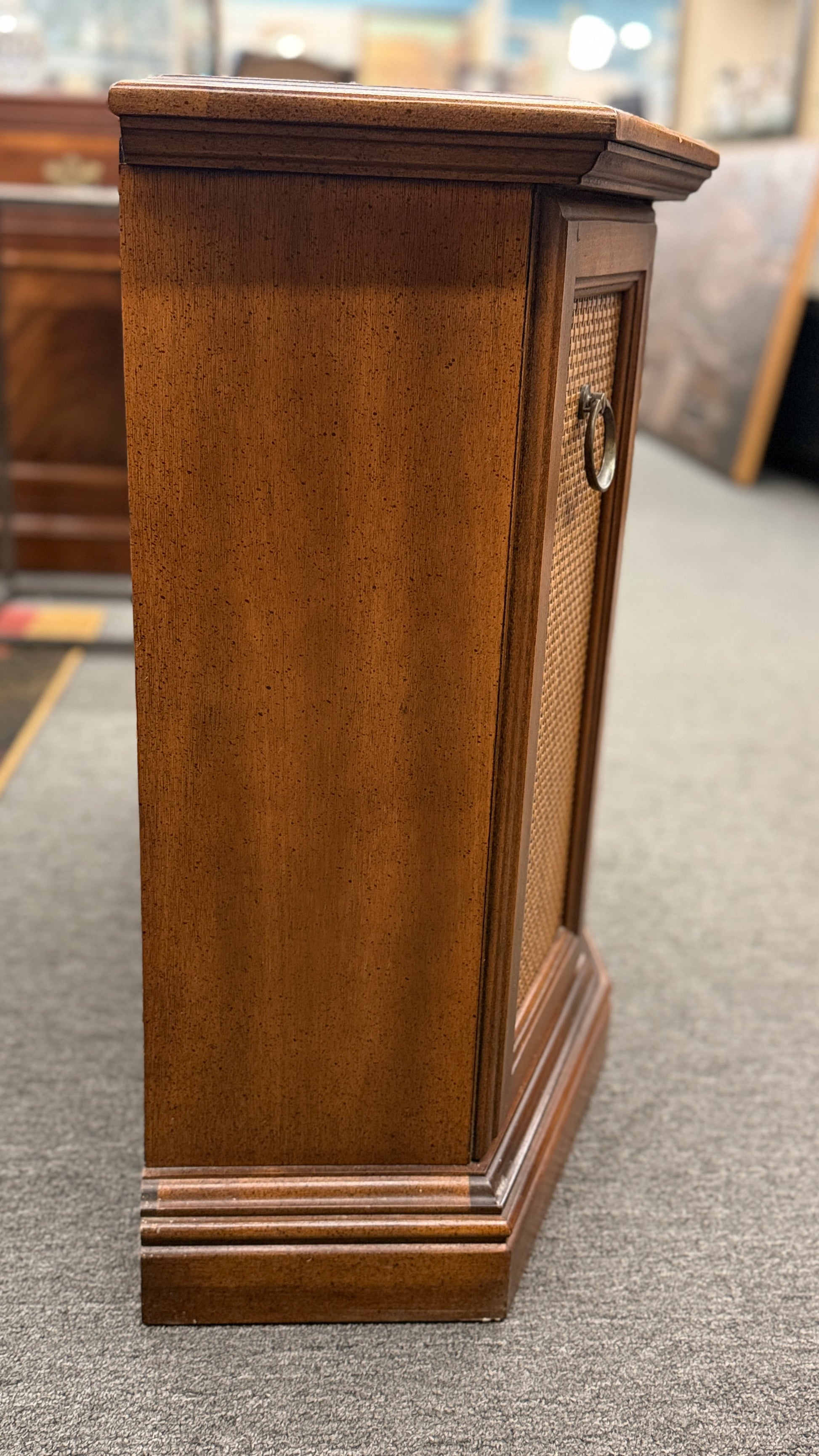 A classic wood accent cabinet featuring three front panels with decorative metal ring-pull hardware and a clean-lined wood frame.