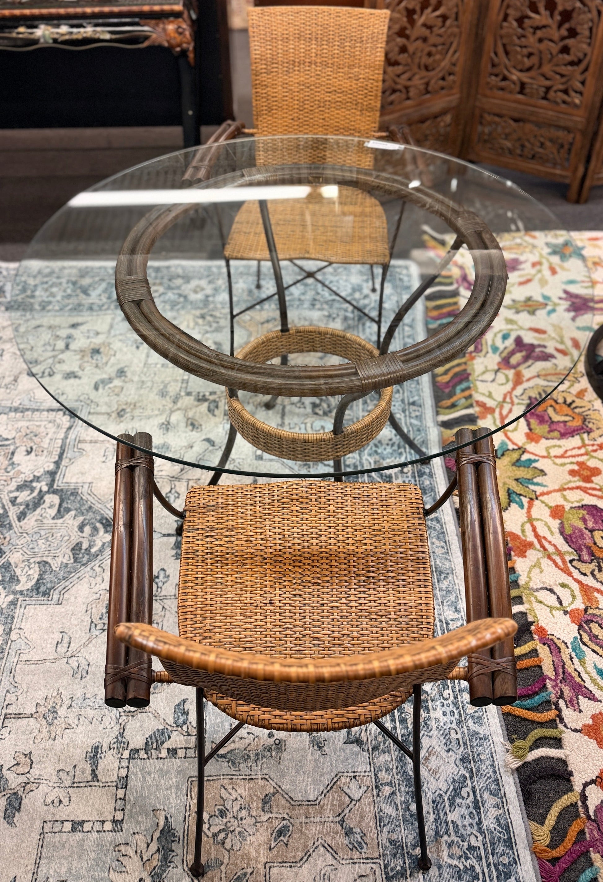 A 3-piece patio bistro set featuring a round glass-top table and two matching armchairs made of rattan and bamboo with curved metal legs.