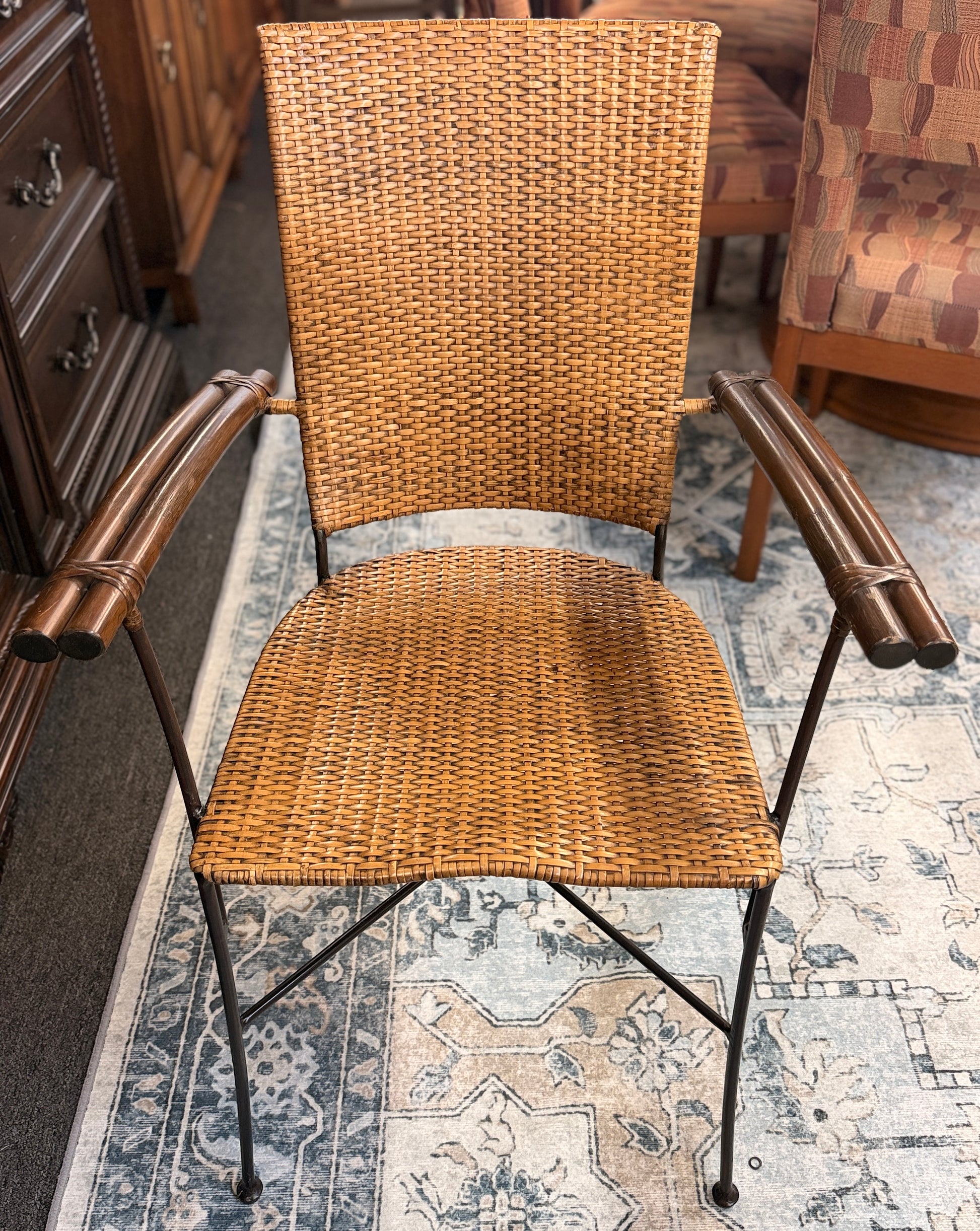 A 3-piece patio bistro set featuring a round glass-top table and two matching armchairs made of rattan and bamboo with curved metal legs.