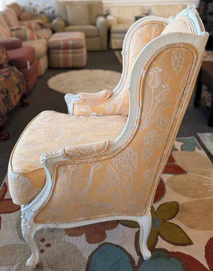 An elegant French provincial-style wingback armchair with an ornate carved white wood frame, tufted-style high backrest, loose seat cushion, and curved cabriole legs.