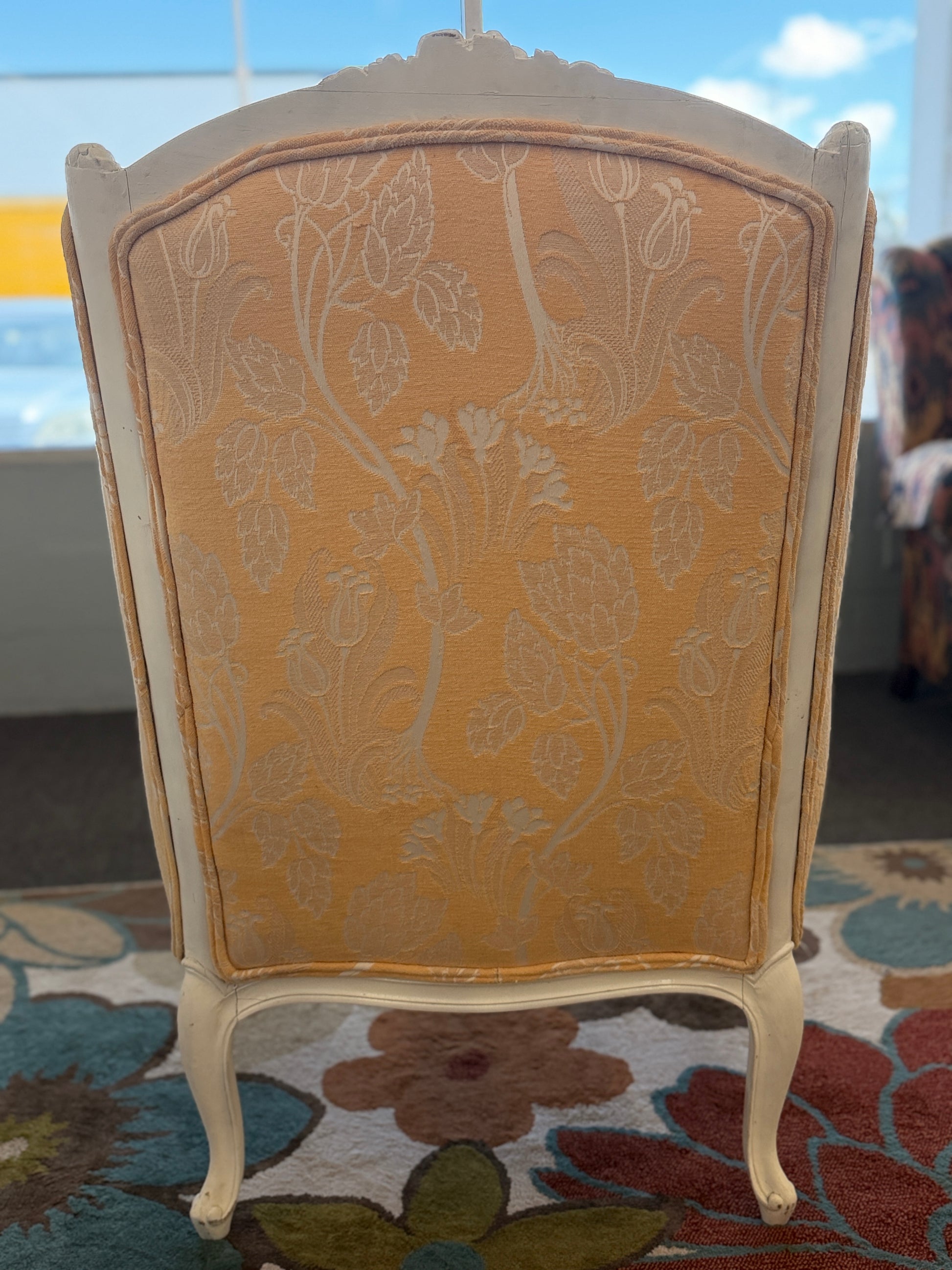 An elegant French provincial-style wingback armchair with an ornate carved white wood frame, tufted-style high backrest, loose seat cushion, and curved cabriole legs.
