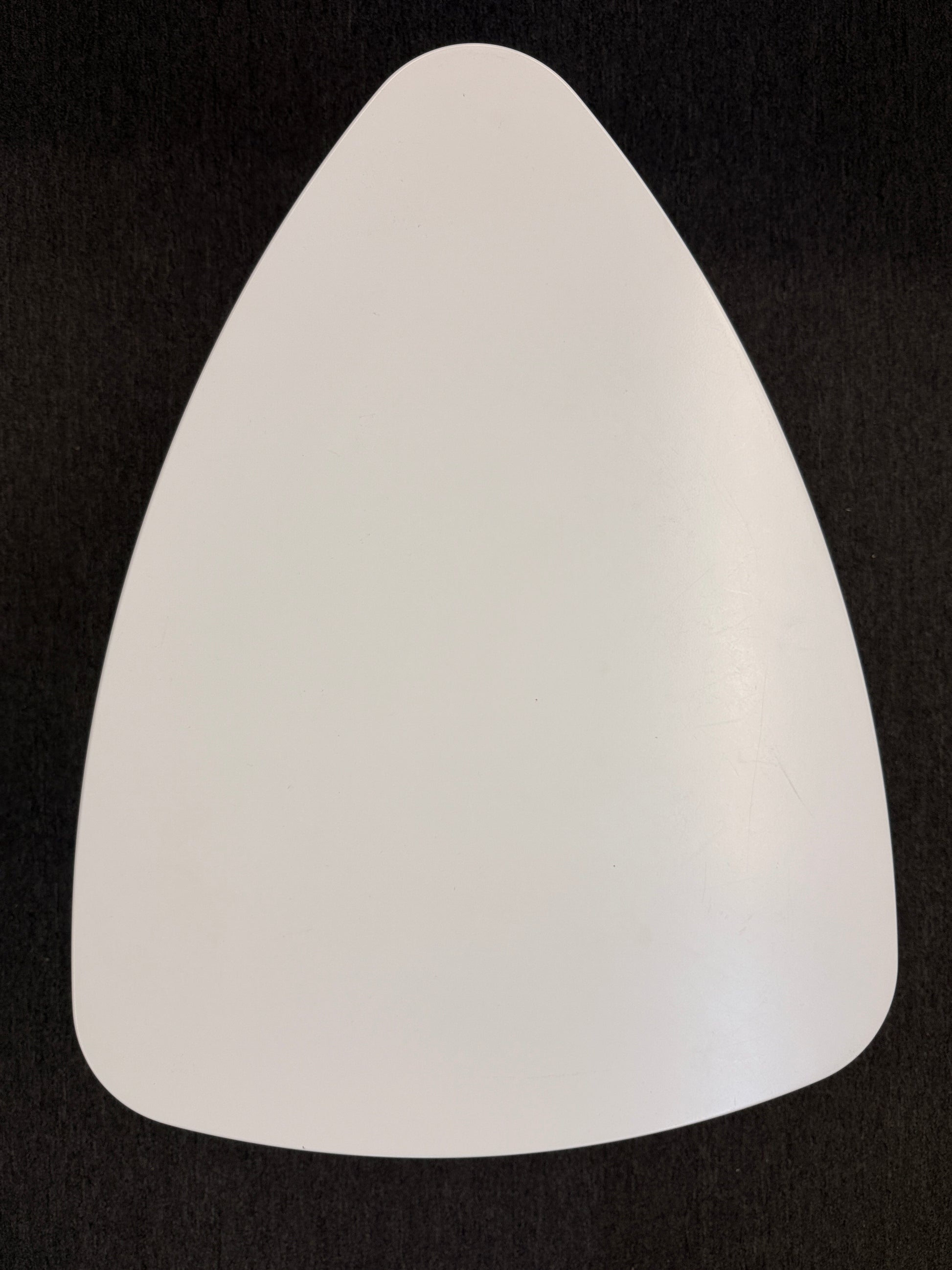 A retro-inspired triangular end table featuring a smooth white guitar-pick-shaped top supported by three splayed, tapered dark wood legs.