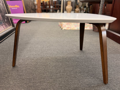 A retro-inspired triangular end table featuring a smooth white guitar-pick-shaped top supported by three splayed, tapered dark wood legs.