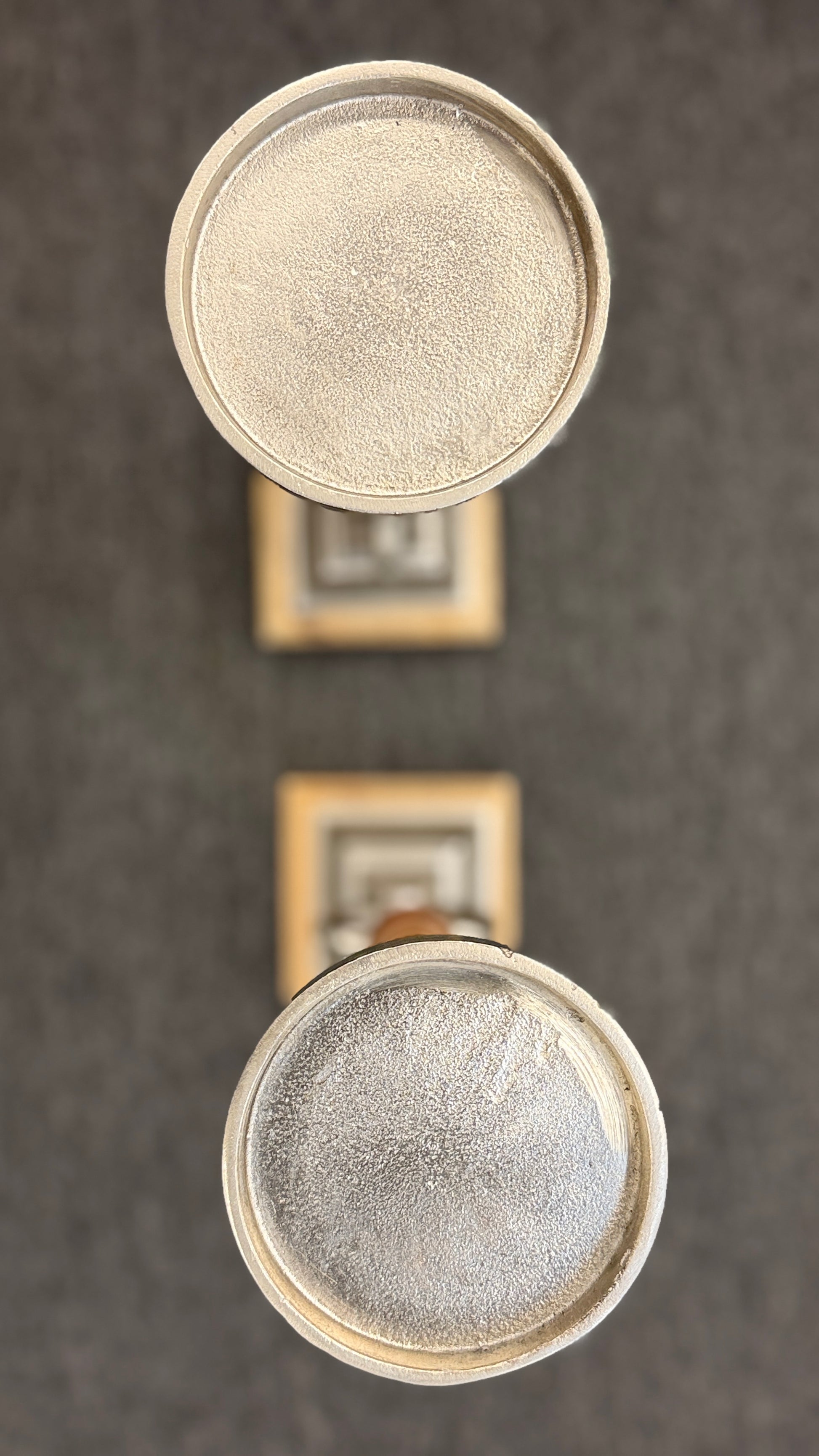 A pair of tall, eclectic pillar candle holders featuring turned wooden spindles, cast-metal open-ring accents, and tiered square plinth bases.
