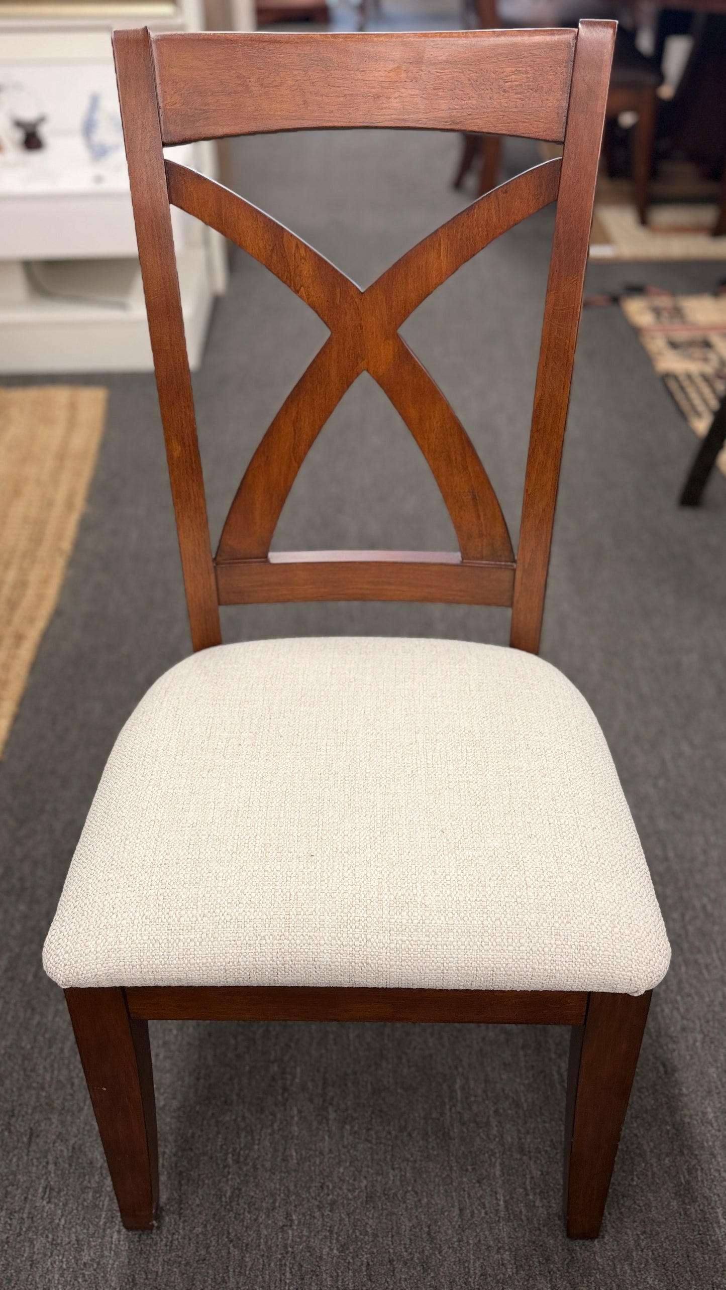 A traditional rectangular wooden dining table with an extendable leaf, twin turned pedestal bases, and six matching X-back dining chairs with light padded seats.