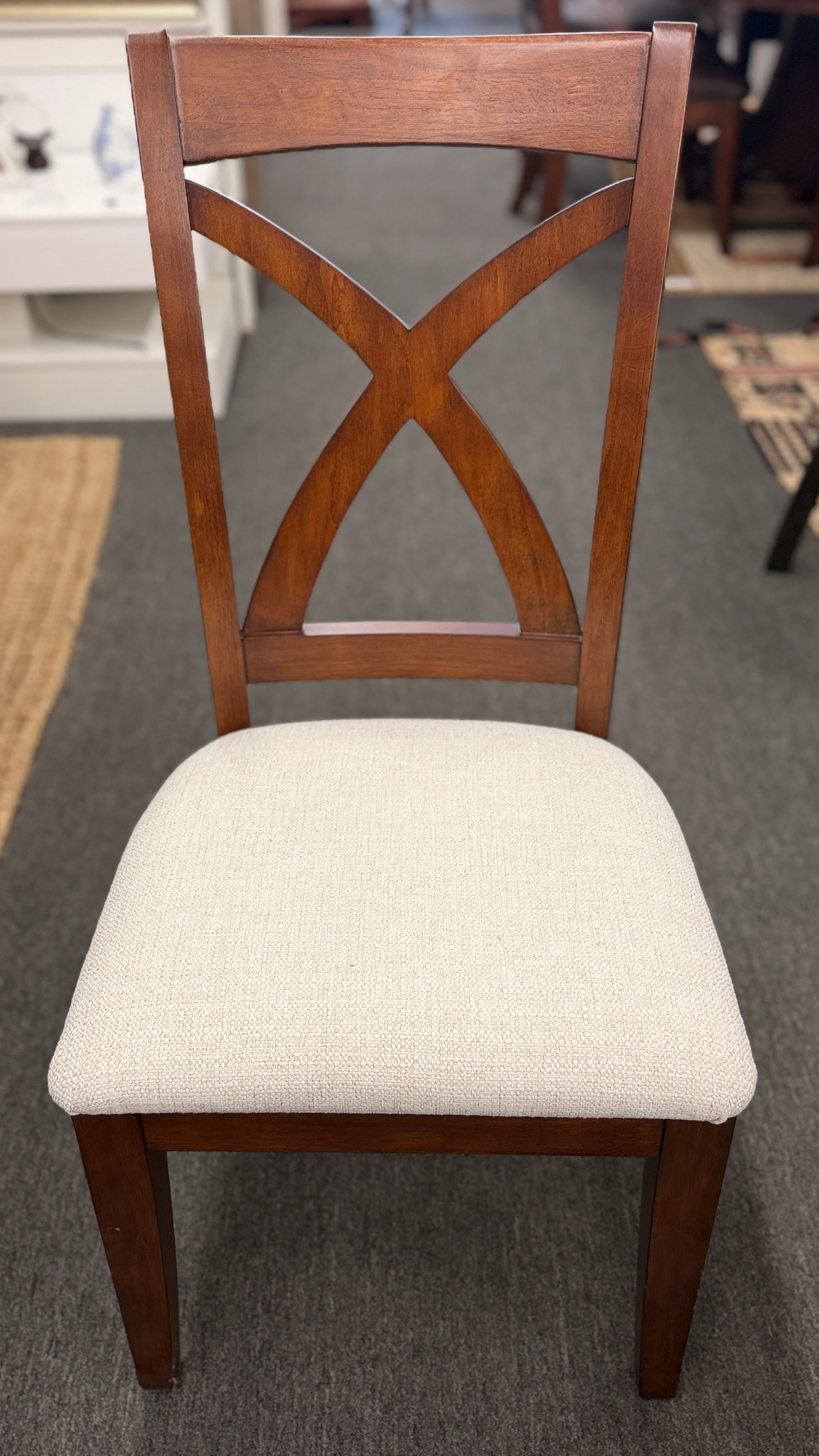 A traditional rectangular wooden dining table with an extendable leaf, twin turned pedestal bases, and six matching X-back dining chairs with light padded seats.