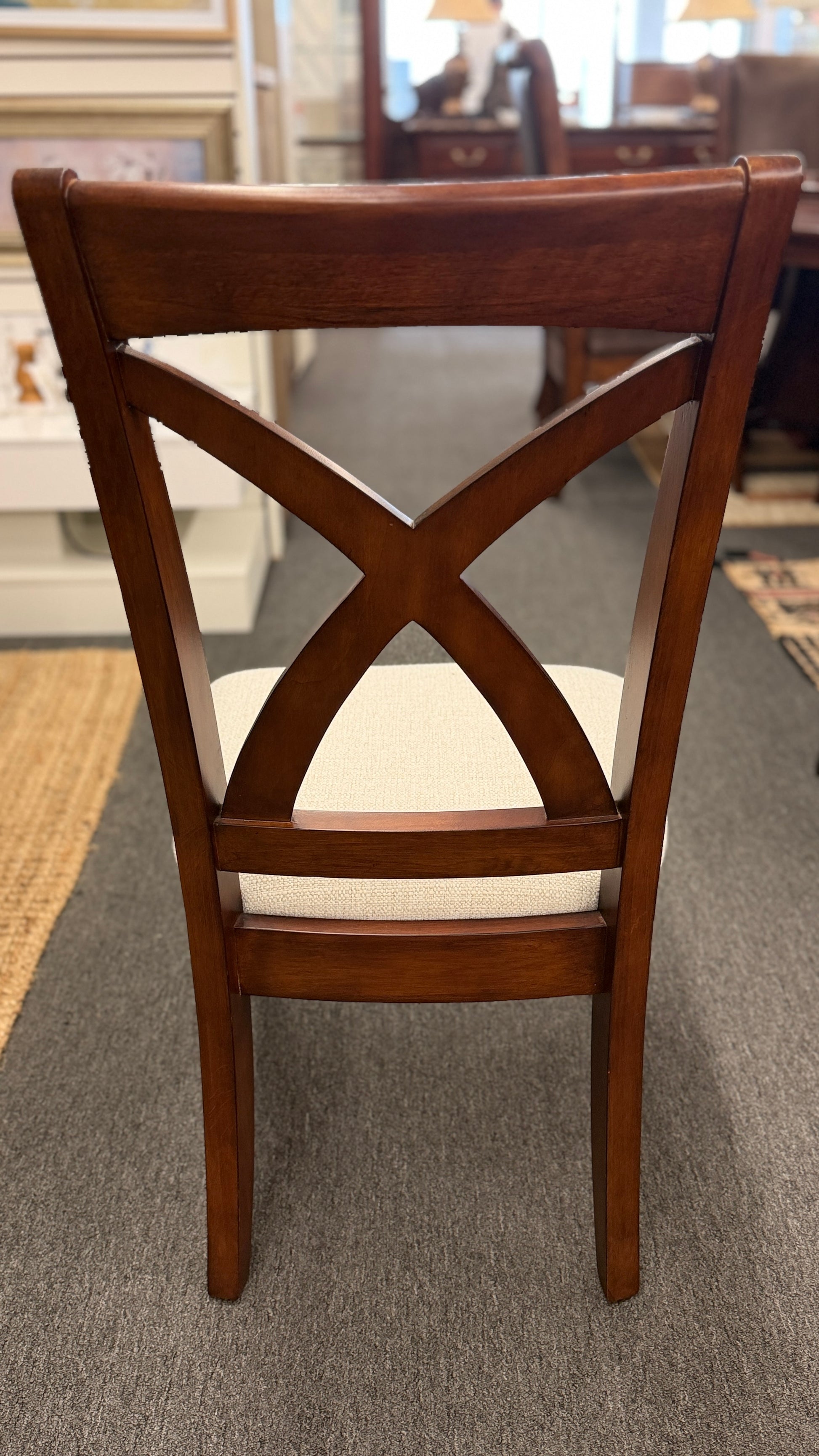 A traditional rectangular wooden dining table with an extendable leaf, twin turned pedestal bases, and six matching X-back dining chairs with light padded seats.