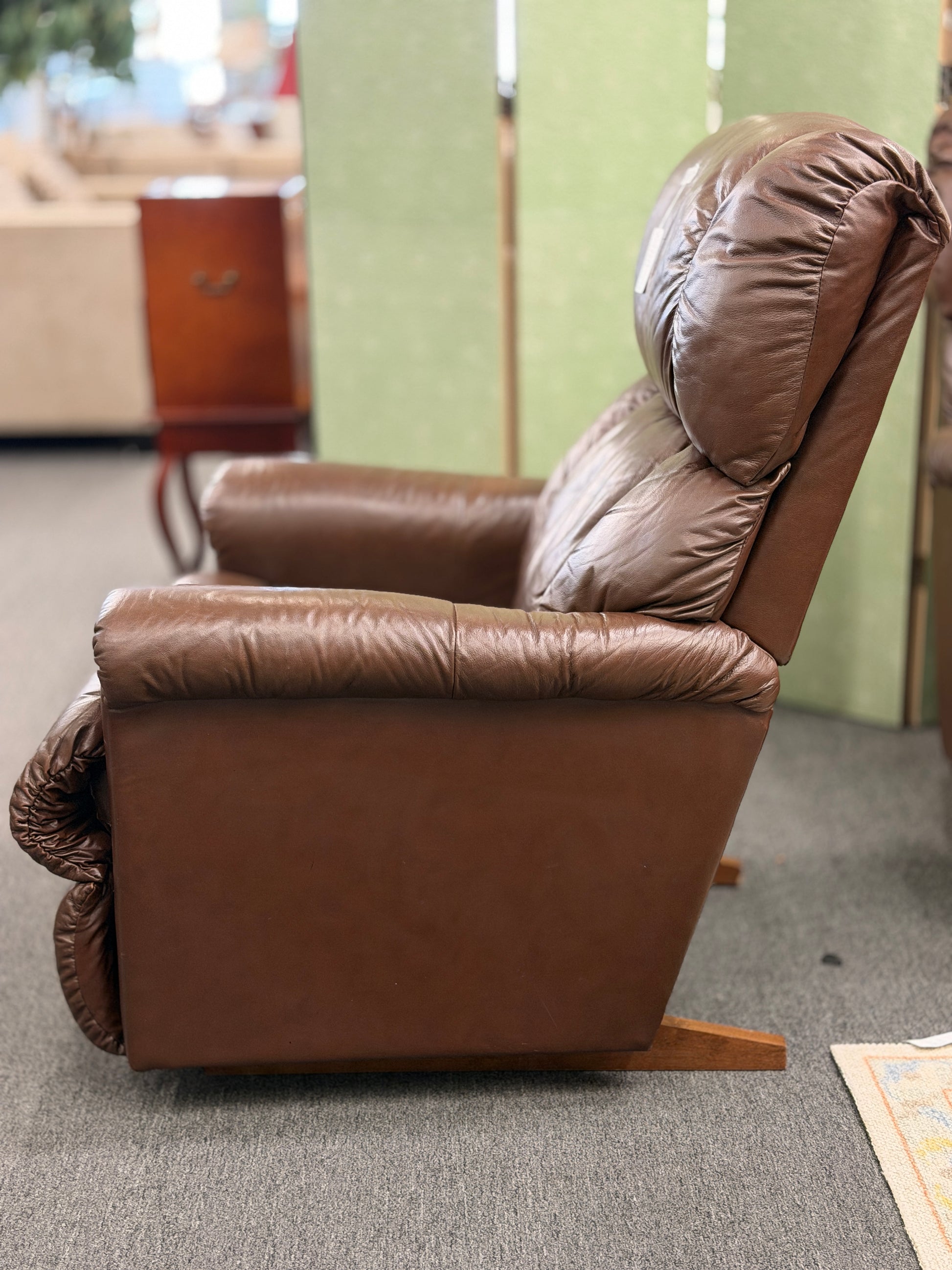 A plush, overstuffed brown leather recliner chair with thick pillowy back cushions and traditional rolled arms.