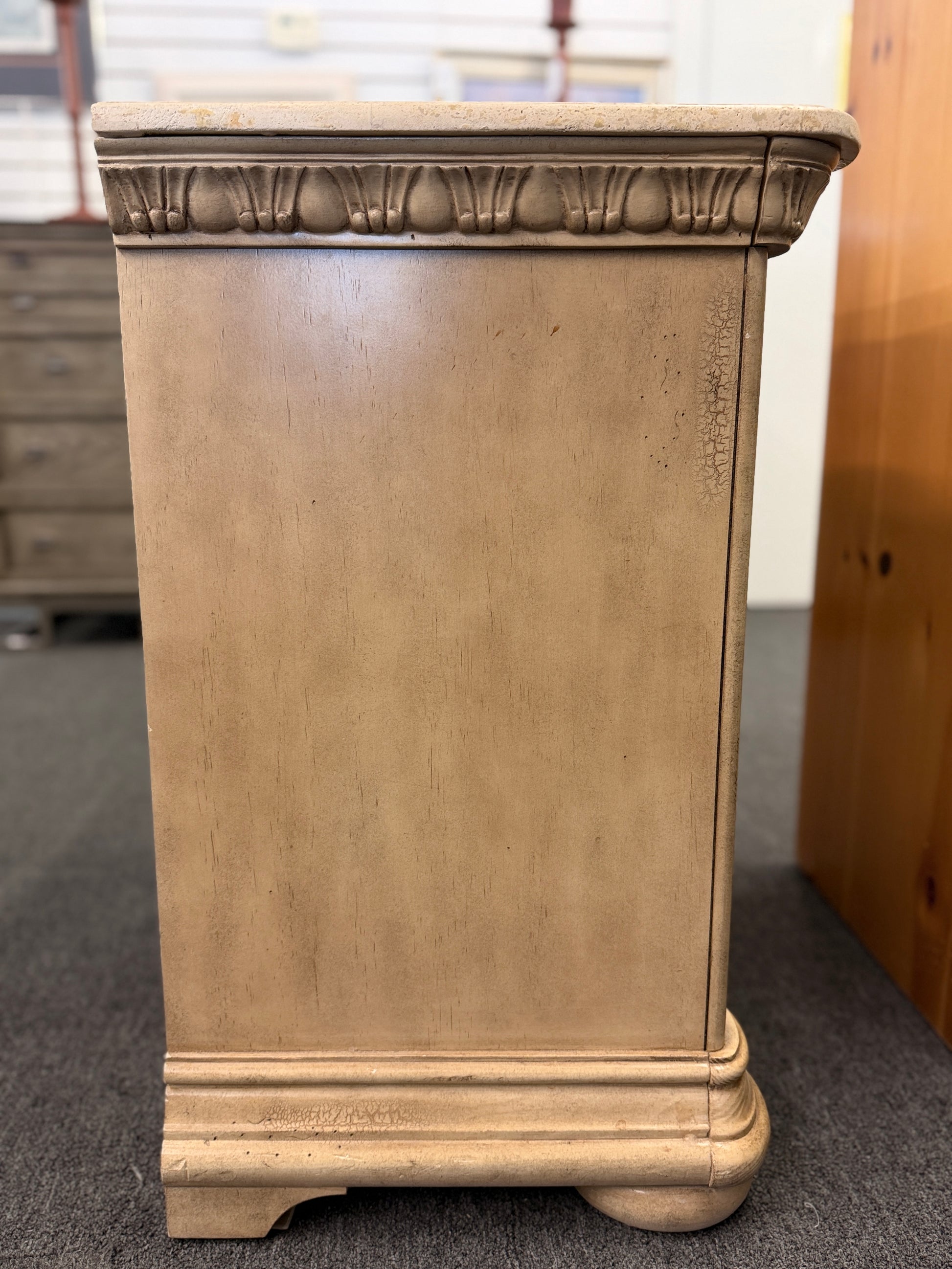 A traditional antique-style nightstand featuring a solid marble top, three serpentine-front drawers, fluted side pilasters, and an antiqued distressed painted finish.