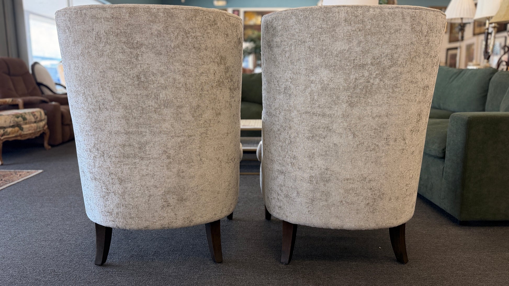 Matching pair of transitional wingback accent armchairs upholstered in textured light beige fabric with dark brown tapered wooden legs.