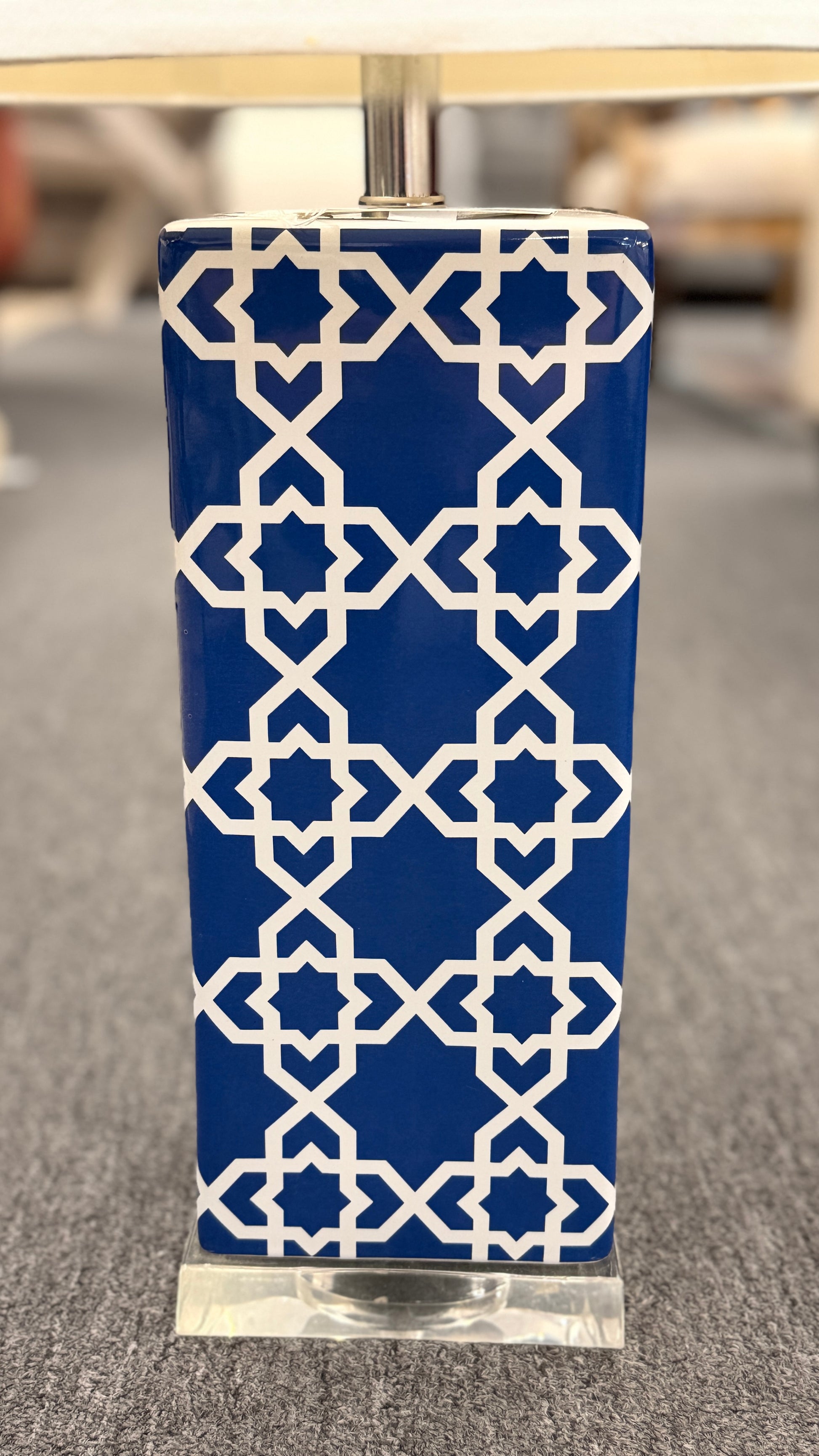 Blue and white ceramic table lamp featuring a geometric trellis pattern, rectangular column base, clear square plinth, and white fabric drum shade.