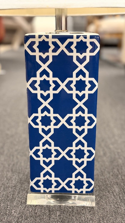 Blue and white ceramic table lamp featuring a geometric trellis pattern, rectangular column base, clear square plinth, and white fabric drum shade.