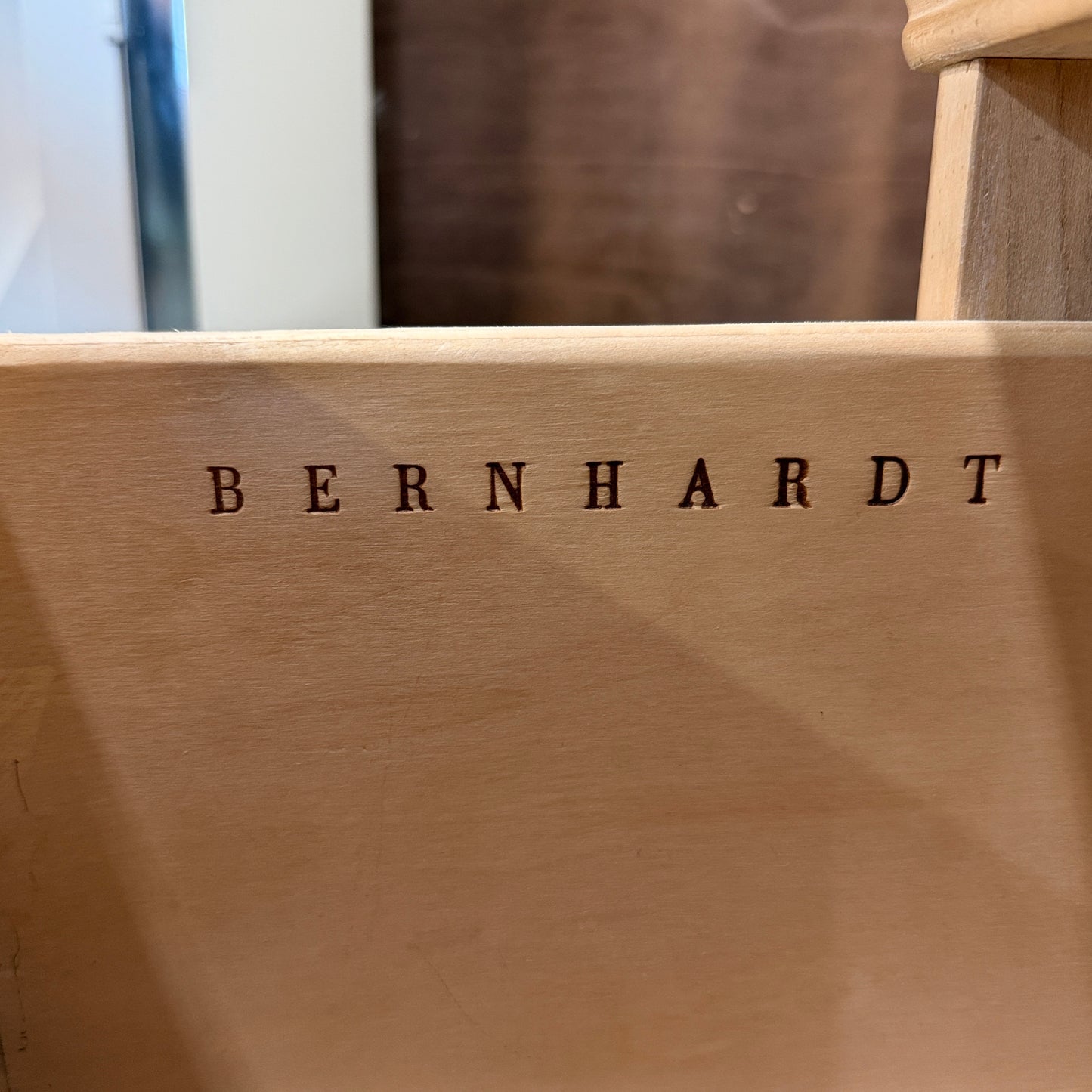 Bernhardt three-drawer wood nightstand with a light finish, routed drawer details, brass knobs, a brass bail pull, and a scalloped base.