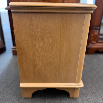 Bernhardt three-drawer wood nightstand with a light finish, routed drawer details, brass knobs, a brass bail pull, and a scalloped base.