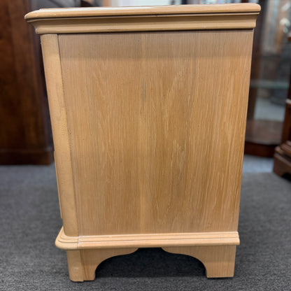 Bernhardt three-drawer wood nightstand with a light finish, routed drawer details, brass knobs, a brass bail pull, and a scalloped base.