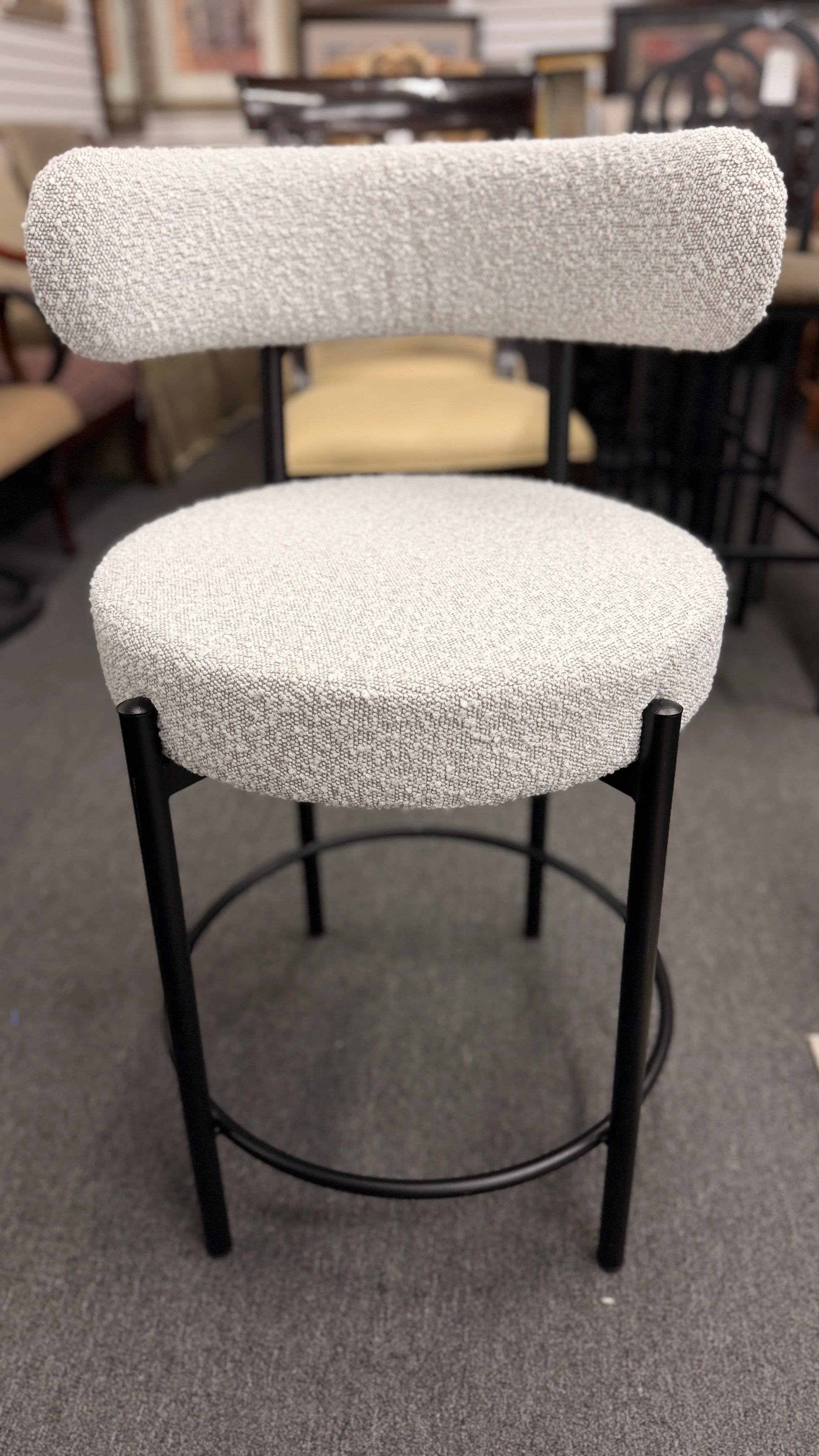 Set of three modern bar stools featuring textured white upholstered seats and curved backrests with sleek black metal frames and built-in footrests.