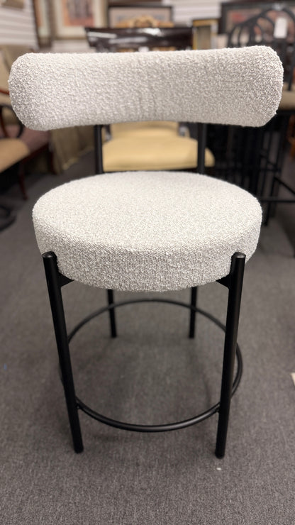 Set of three modern bar stools featuring textured white upholstered seats and curved backrests with sleek black metal frames and built-in footrests.