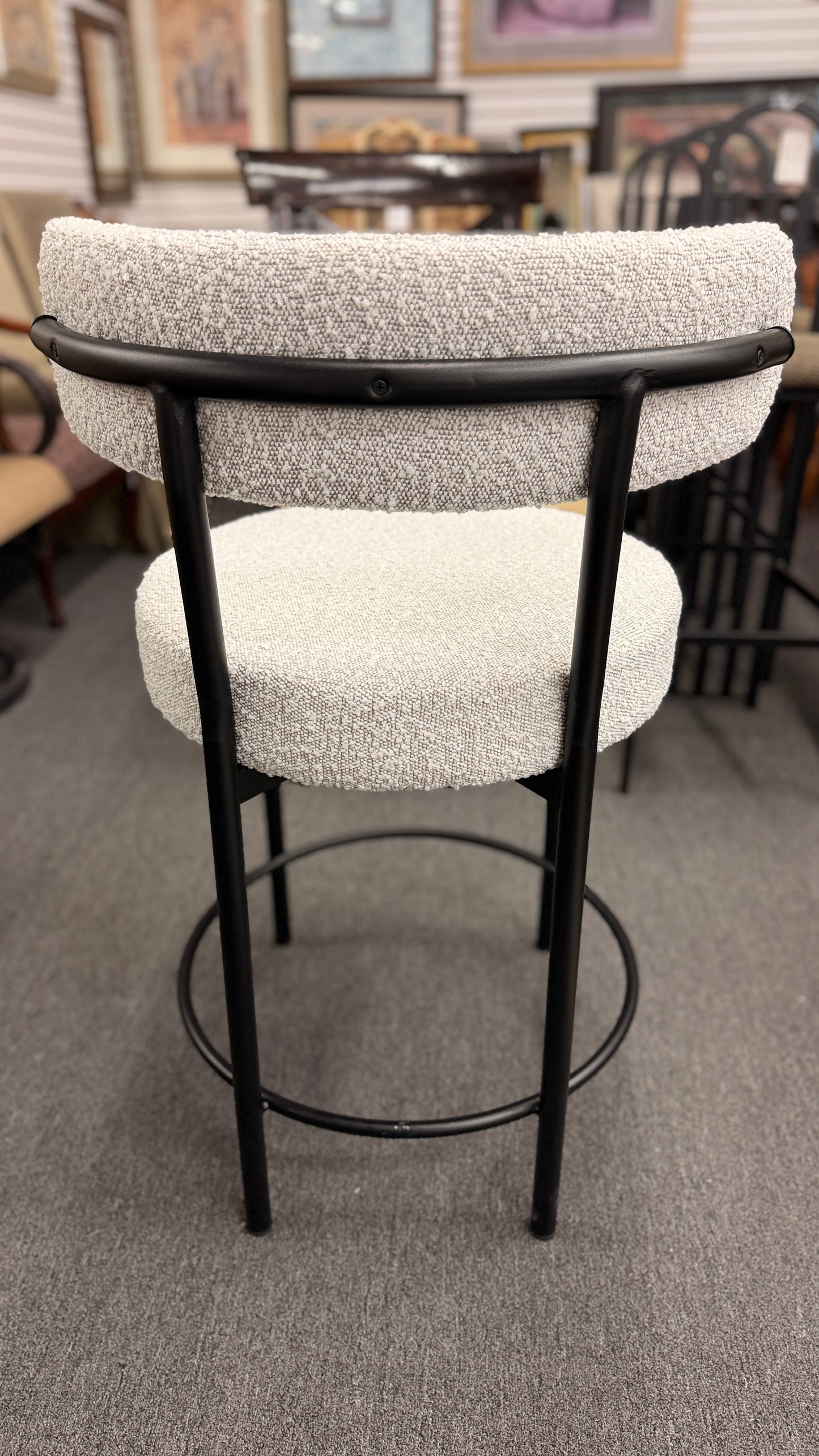 Set of three modern bar stools featuring textured white upholstered seats and curved backrests with sleek black metal frames and built-in footrests.