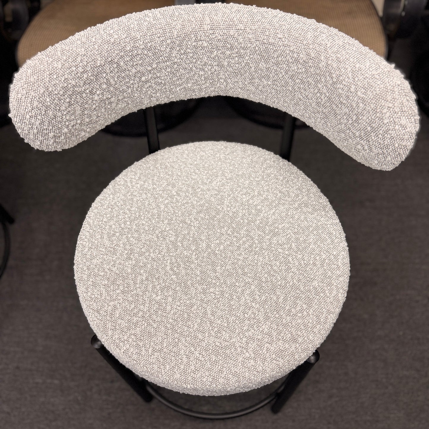 Set of three modern bar stools featuring textured white upholstered seats and curved backrests with sleek black metal frames and built-in footrests.