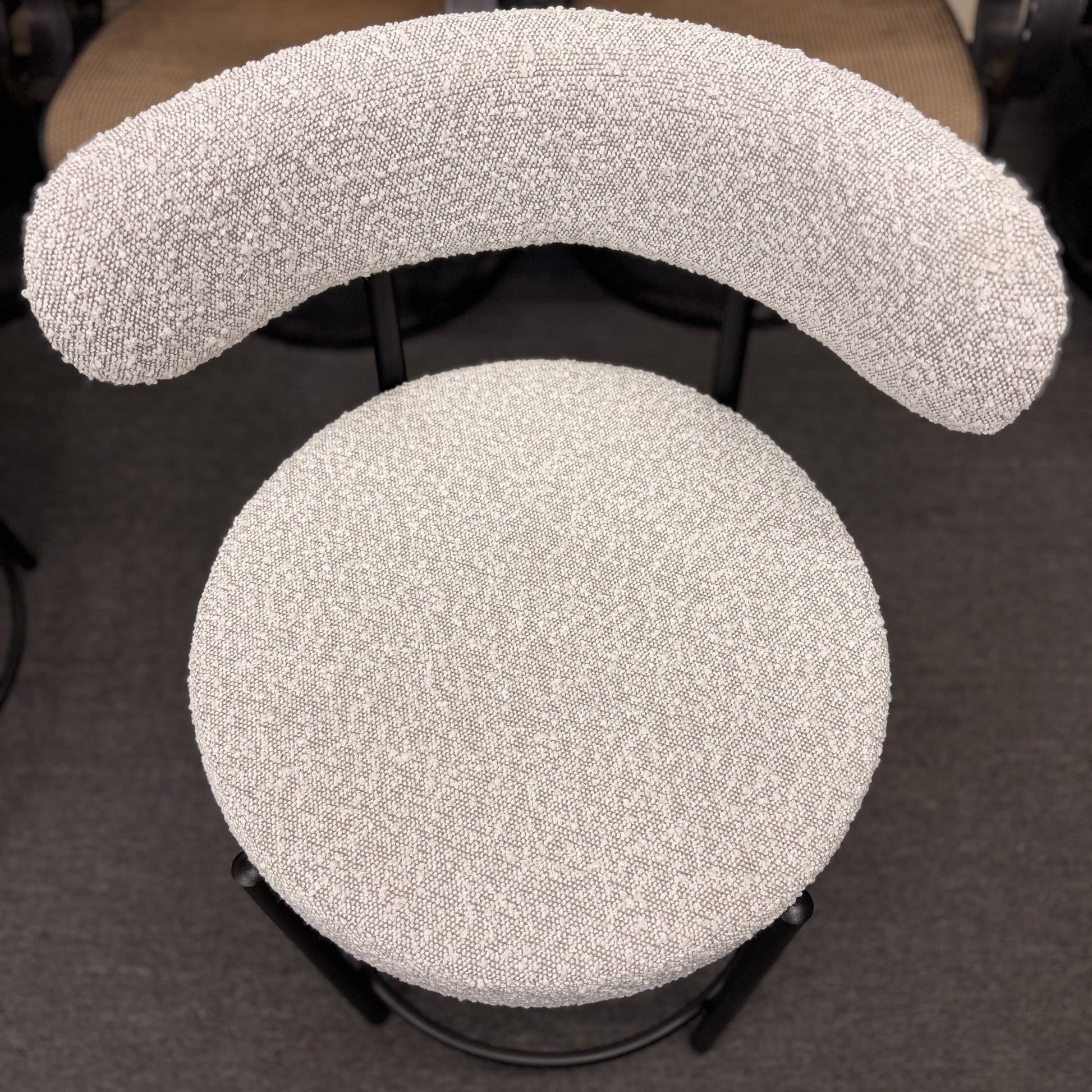 Set of three modern bar stools featuring textured white upholstered seats and curved backrests with sleek black metal frames and built-in footrests.