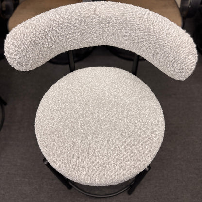 Set of three modern bar stools featuring textured white upholstered seats and curved backrests with sleek black metal frames and built-in footrests.
