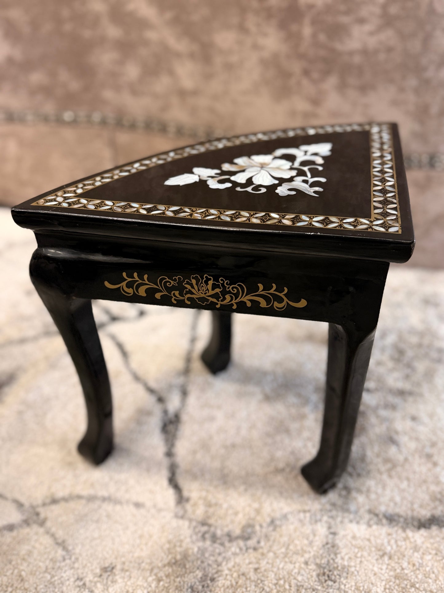 Traditional black lacquer tea table set featuring a round coffee table with a protective glass top, four triangular nesting stools, gold-painted detailing, and mother-of-pearl style floral inlays.