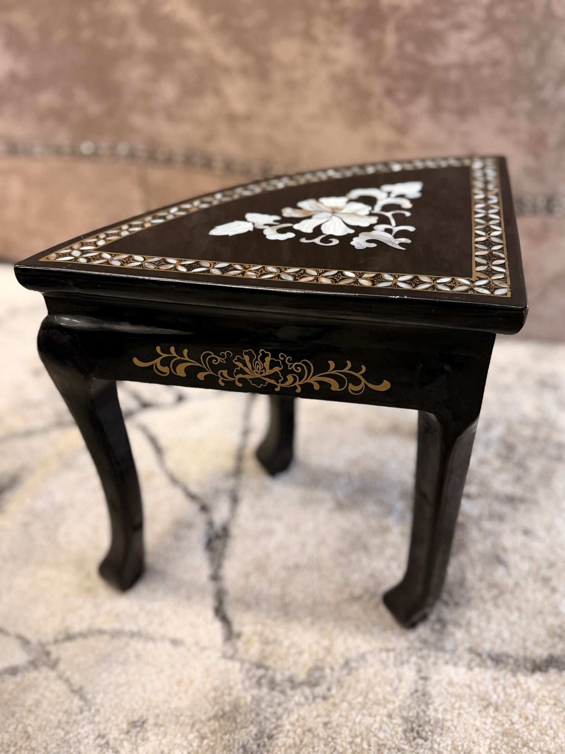 Traditional black lacquer tea table set featuring a round coffee table with a protective glass top, four triangular nesting stools, gold-painted detailing, and mother-of-pearl style floral inlays.