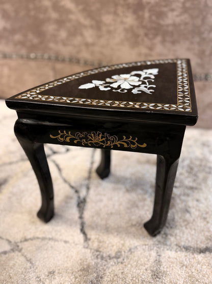 Traditional black lacquer tea table set featuring a round coffee table with a protective glass top, four triangular nesting stools, gold-painted detailing, and mother-of-pearl style floral inlays.