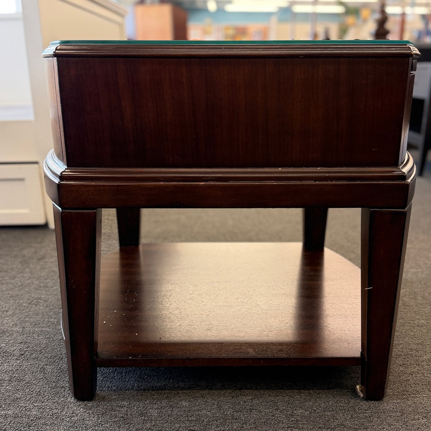 Dark wood nightstand featuring a glass insert top, a single drawer with a silver ring pull, and an open lower display shelf.
