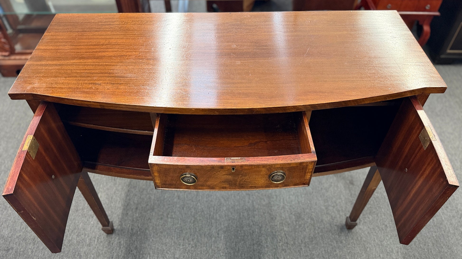Traditional wood server featuring three front storage compartments with brass ring pulls, a scalloped bottom edge, and distinctive circular wood grain side panels.